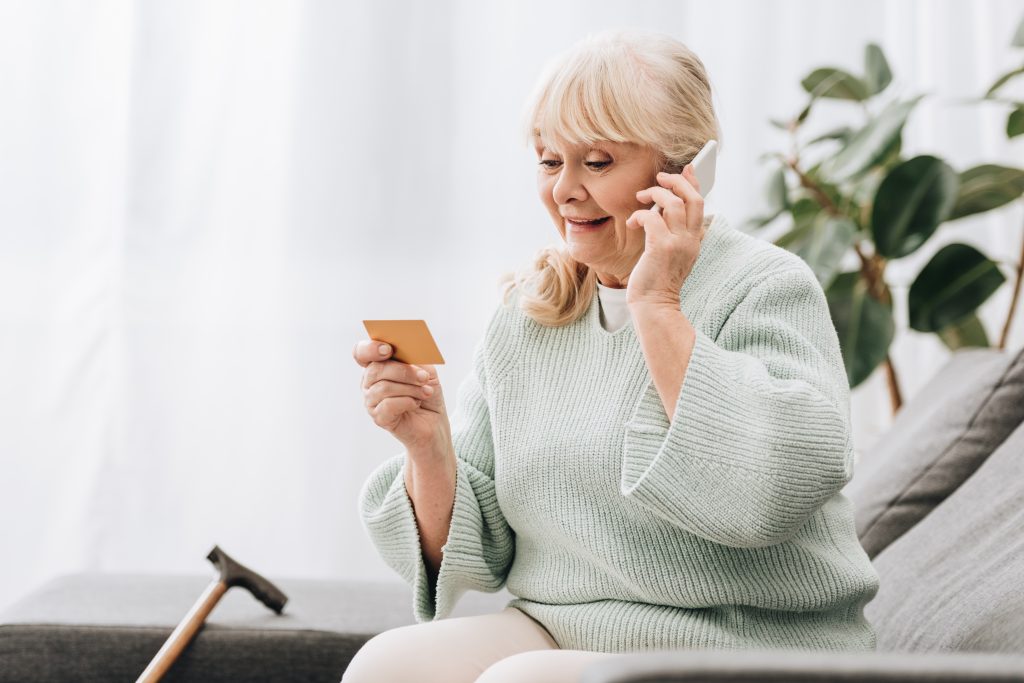 Seniorin am Telefon hält Visitenkarte